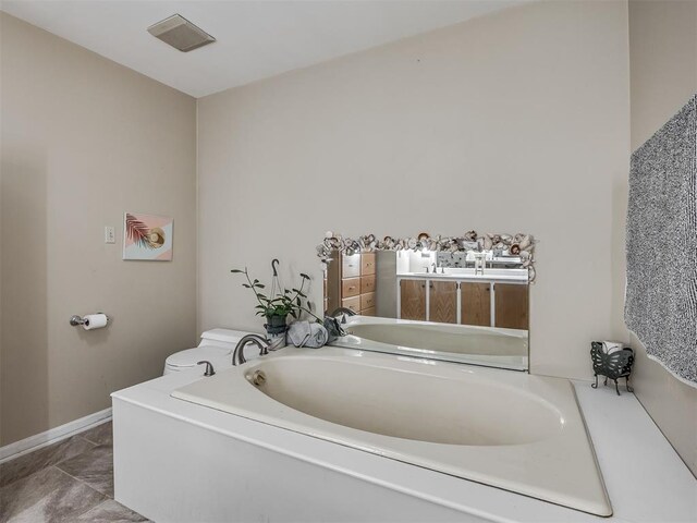 2604 Jeannes Trl, Edmond, OK 73012 - bathroom with a garden tub, toilet, and baseboards