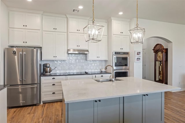 29731 Jade St, Cashion, OK 73016 - kitchen featuring stainless steel appliances, a chandelier, light wood finished floors, white cabinetry, and hanging light fixtures