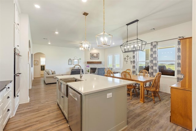 29731 Jade St, Cashion, OK 73016 - kitchen featuring stainless steel appliances, open floor plan, arched walkways, light wood-type flooring, and white cabinetry