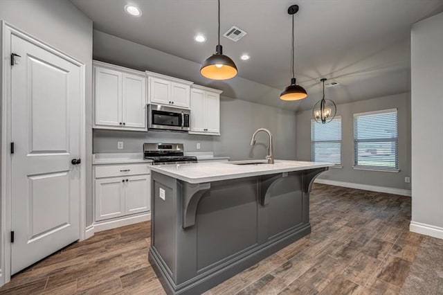 2000 W Flintlock Way, Mustang, OK 73065 - kitchen with appliances with stainless steel finishes, a sink, light countertops, a center island with sink, and white cabinets