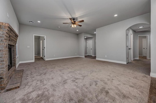 2000 W Flintlock Way, Mustang, OK 73065 - unfurnished living room with a brick fireplace, arched walkways, a ceiling fan, carpet, and recessed lighting