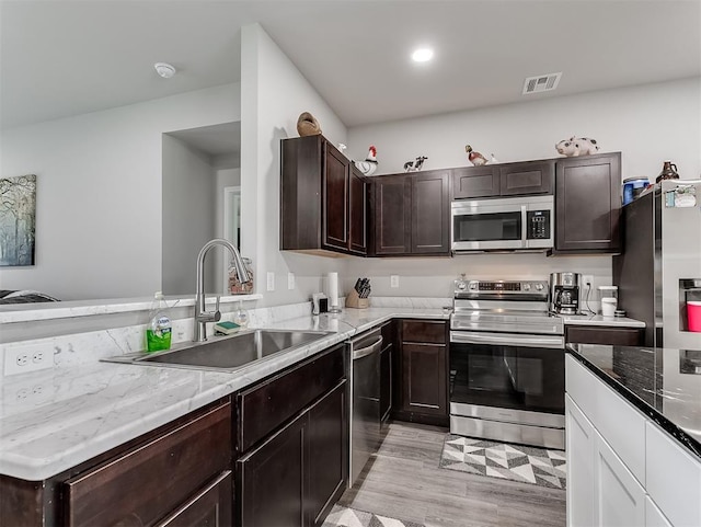 42173 N Max Henry Dr, Shawnee, OK 74804 - kitchen featuring stainless steel appliances, a sink, dark brown cabinetry, light stone countertops, and light wood-style flooring