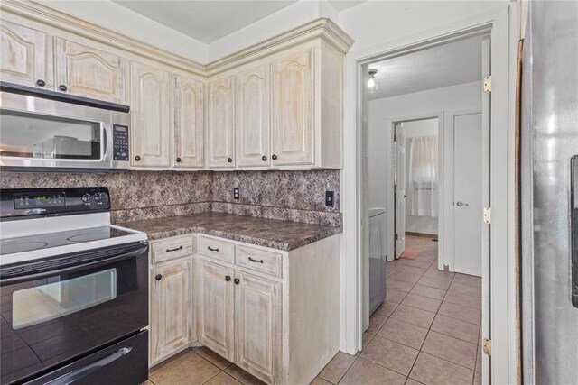 2020 Lyle Rd, Weatherford, OK 73096 - kitchen with stainless steel appliances, dark countertops, cream cabinetry, light tile patterned floors, and decorative backsplash