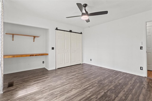 2020 Lyle Rd, Weatherford, OK 73096 - unfurnished bedroom featuring a barn door, wood finished floors, a ceiling fan, a closet, and baseboards
