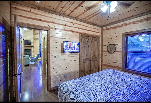 56 Muscadine Trl, Broken Bow, OK 74728 - bedroom featuring wooden walls, wood ceiling, wood-type flooring, a fireplace, and a ceiling fan
