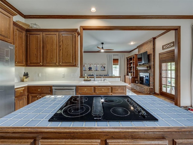 13925 Middleberry Rd, Edmond, OK 73013 - kitchen featuring a sink, appliances with stainless steel finishes, tile counters, ornamental molding, and healthy amount of natural light