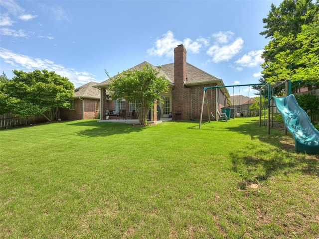 13925 Middleberry Rd, Edmond, OK 73013 - back of property featuring a playground, brick siding, a chimney, and a patio