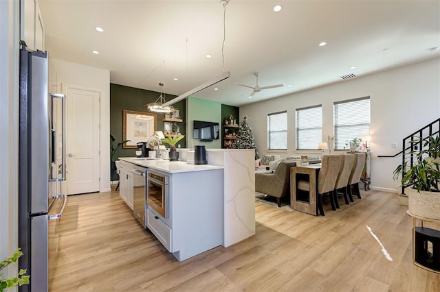 571 S Fretz Ave, Edmond, OK 73003 - kitchen featuring light wood finished floors, a center island with sink, open floor plan, a ceiling fan, and recessed lighting