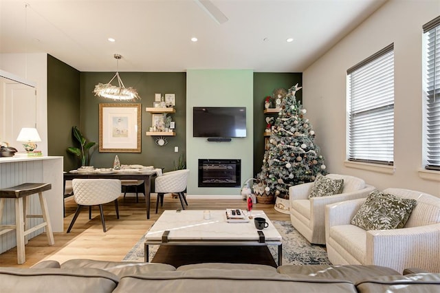 571 S Fretz Ave, Edmond, OK 73003 - living room featuring a chandelier, wood finished floors, healthy amount of natural light, a glass covered fireplace, and recessed lighting