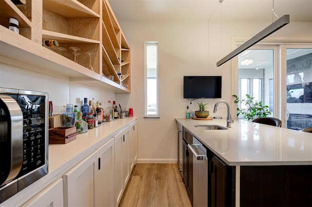 571 S Fretz Ave, Edmond, OK 73003 - kitchen featuring stainless steel microwave, a sink, light wood-style floors, open shelves, and a peninsula