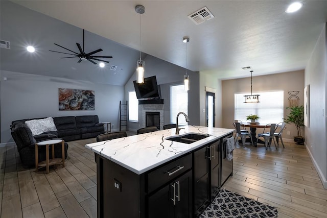 8725 NW Kensington Pl, Lawton, OK 73505 - kitchen with a sink, a stone fireplace, dishwasher, light wood-style flooring, and vaulted ceiling
