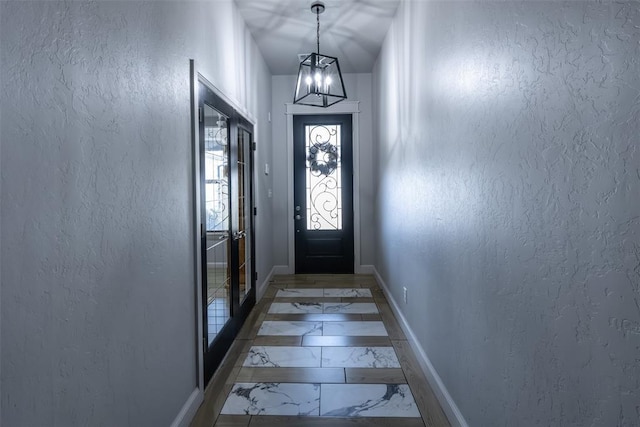 8725 NW Kensington Pl, Lawton, OK 73505 - entryway featuring baseboards, light marble finish floors, a chandelier, and a textured wall