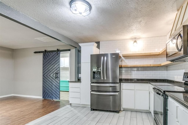 816 Woodbury Dr, Edmond, OK 73034 - kitchen featuring stainless steel fridge, electric range oven, a barn door, light wood-style floors, and dark countertops