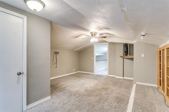 816 Woodbury Dr, Edmond, OK 73034 - bonus room featuring a ceiling fan, a textured ceiling, carpet floors, vaulted ceiling, and a textured wall
