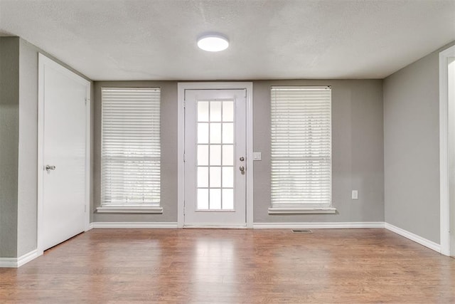816 Woodbury Dr, Edmond, OK 73034 - doorway to outside featuring wood finished floors and a textured ceiling