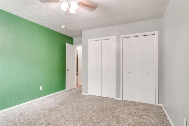 816 Woodbury Dr, Edmond, OK 73034 - unfurnished bedroom featuring two closets, carpet flooring, a textured ceiling, and a ceiling fan