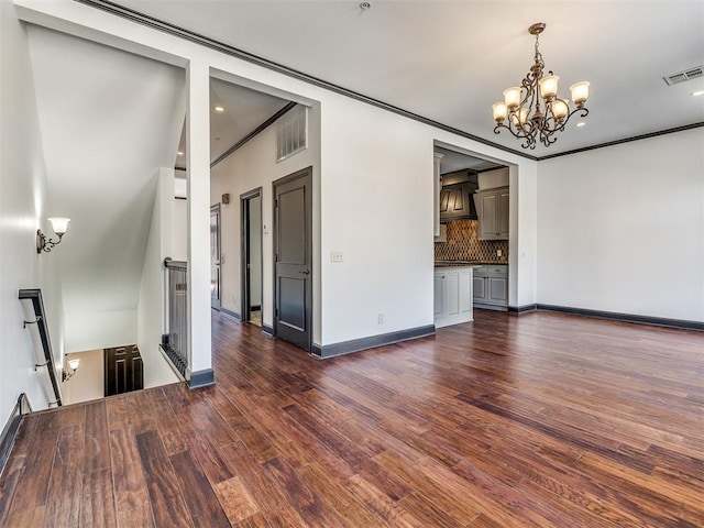 23 NE 3rd St, Oklahoma City, OK 73104 - unfurnished living room featuring a chandelier, dark wood-type flooring, baseboards, and crown molding