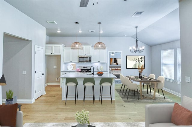 3232 Pagoda Pead Dr, Yukon, OK 73099 - kitchen featuring stainless steel appliances, white cabinets, light wood-style flooring, light countertops, and a breakfast bar area