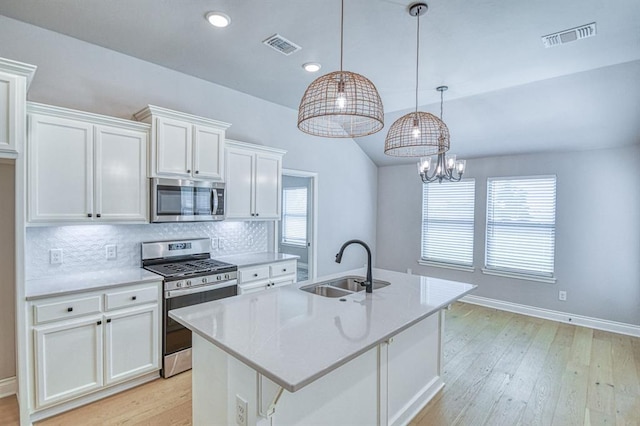3232 Pagoda Pead Dr, Yukon, OK 73099 - kitchen featuring appliances with stainless steel finishes, light wood-type flooring, white cabinets, backsplash, and a kitchen island with sink