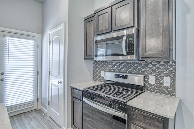 11100 NW 131st St, Yukon, OK 73099 - kitchen with stainless steel appliances, backsplash, light stone countertops, light wood-style flooring, and dark brown cabinetry
