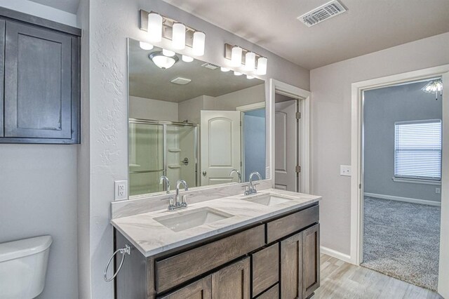 11100 NW 131st St, Yukon, OK 73099 - bathroom featuring double vanity, toilet, an enclosed shower, wood finished floors, and baseboards