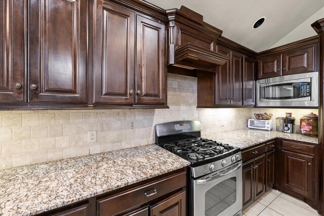 3401 First Capitol Cir, Guthrie, OK 73044 - kitchen with stainless steel appliances, backsplash, light stone countertops, dark brown cabinets, and vaulted ceiling