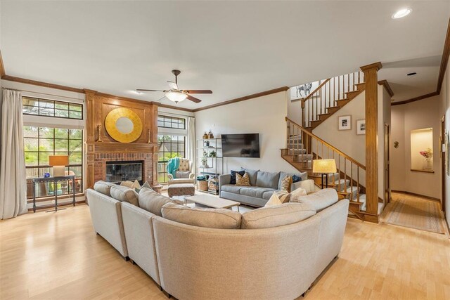 4001 Innsbrook Ct, Norman, OK 73072 - living room featuring crown molding, light wood-style flooring, a ceiling fan, a fireplace, and plenty of natural light