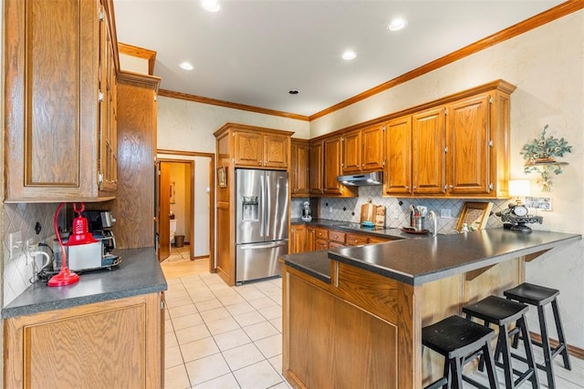 4001 Innsbrook Ct, Norman, OK 73072 - kitchen with stainless steel fridge, under cabinet range hood, a peninsula, dark countertops, and a kitchen breakfast bar