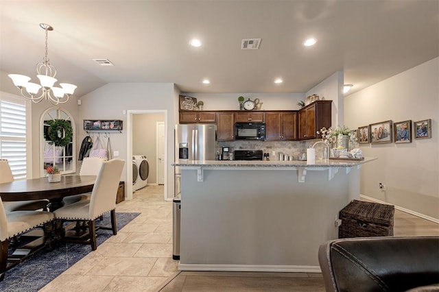 11513 SW 26th St, Yukon, OK 73099 - kitchen featuring independent washer and dryer, black microwave, stainless steel fridge, range, and a peninsula