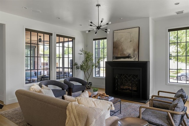 1801 Runway Blvd, Oklahoma City, OK 73108 - living room featuring plenty of natural light, wood finished floors, a fireplace with raised hearth, a chandelier, and recessed lighting