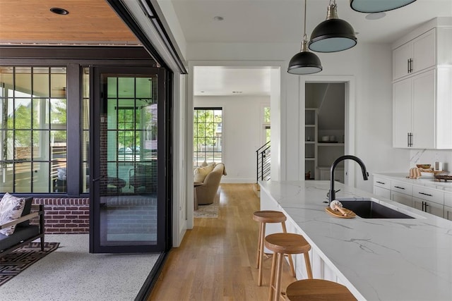 1801 Runway Blvd, Oklahoma City, OK 73108 - kitchen with white cabinets, light stone countertops, hanging light fixtures, light wood-style floors, and a breakfast bar area