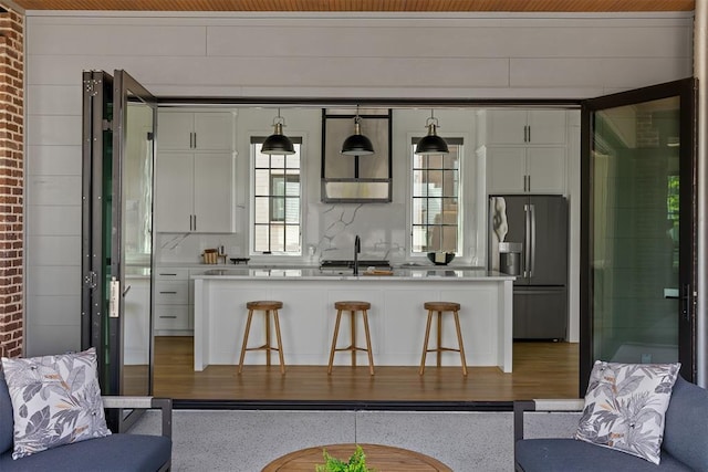 1801 Runway Blvd, Oklahoma City, OK 73108 - kitchen with stainless steel refrigerator with ice dispenser, white cabinets, light countertops, a breakfast bar, and brick wall