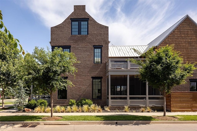 1801 Runway Blvd, Oklahoma City, OK 73108 - view of front of house with a standing seam roof, a balcony, a sunroom, brick siding, and a metal roof