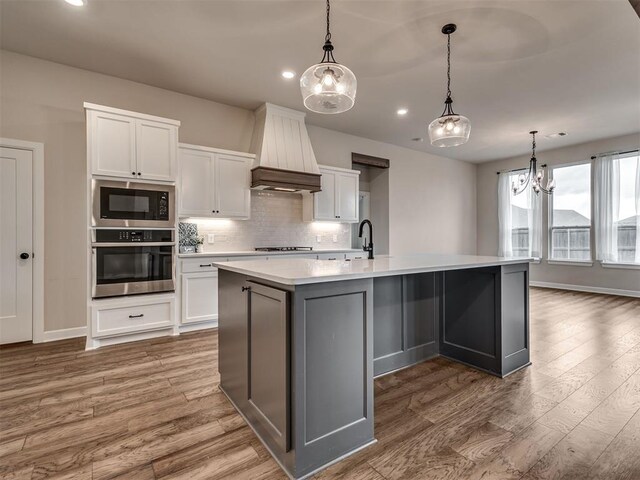 915 Kings Canyon Rd, Norman, OK 73071 - kitchen with stainless steel oven, premium range hood, a chandelier, recessed lighting, and cooktop