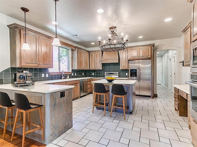 1031 Hidden Valley Ln, Choctaw, OK 73020 - kitchen with appliances with stainless steel finishes, custom range hood, a breakfast bar area, arched walkways, and a peninsula