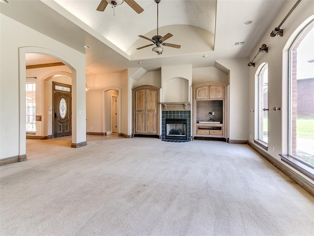 1031 Hidden Valley Ln, Choctaw, OK 73020 - unfurnished living room featuring light carpet, a ceiling fan, a tile fireplace, vaulted ceiling, and arched walkways