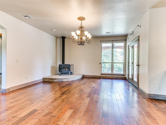 1031 Hidden Valley Ln, Choctaw, OK 73020 - unfurnished living room with hardwood / wood-style floors, a wood stove, and a chandelier