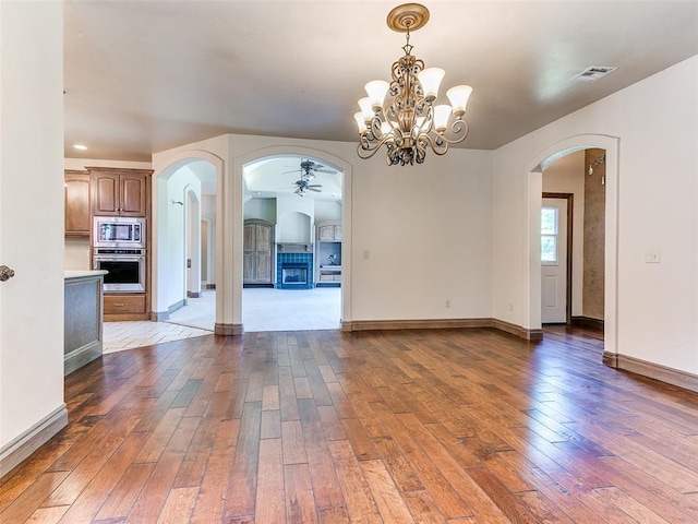 1031 Hidden Valley Ln, Choctaw, OK 73020 - unfurnished room featuring dark wood-style floors, arched walkways, ceiling fan, and a chandelier