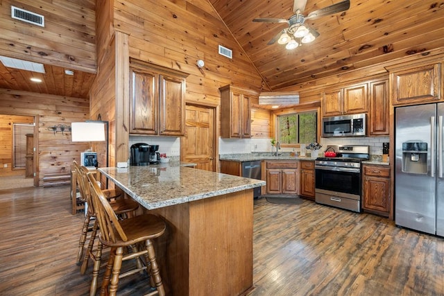 184 Almond Ln, Hochatown, OK 74728 - kitchen with appliances with stainless steel finishes, lofted ceiling, a peninsula, brown cabinetry, and wood ceiling