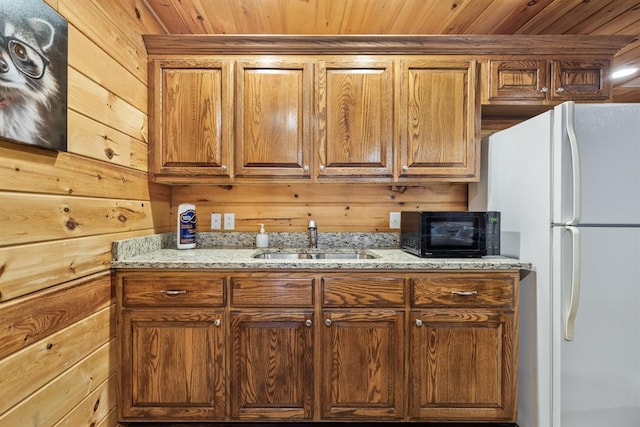 184 Almond Ln, Hochatown, OK 74728 - kitchen with a sink, freestanding refrigerator, wood walls, light stone counters, and wood ceiling