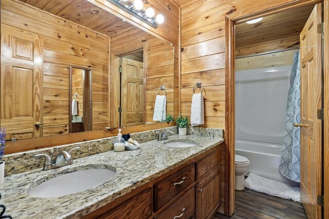 184 Almond Ln, Hochatown, OK 74728 - full bathroom with double vanity, toilet, wood walls, wood finished floors, and shower / bath combo with shower curtain