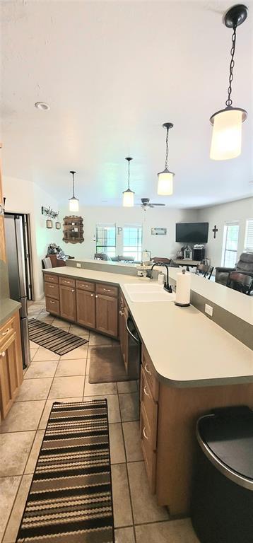 319 W Cedar Ln, Minco, OK 73059 - kitchen featuring a sink, freestanding refrigerator, open floor plan, hanging light fixtures, and light countertops
