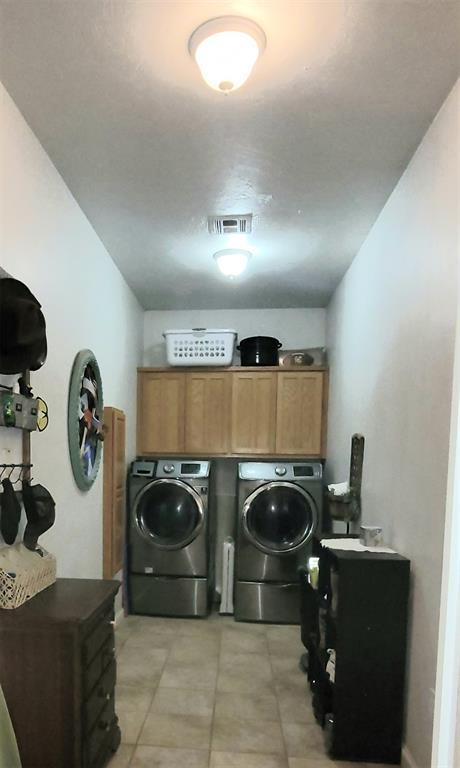 319 W Cedar Ln, Minco, OK 73059 - laundry area with washing machine and clothes dryer, cabinet space, and light tile patterned floors