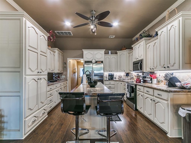 913 E Harrison Ave, Guthrie, OK 73044 - kitchen featuring appliances with stainless steel finishes, a ceiling fan, backsplash, and dark wood finished floors