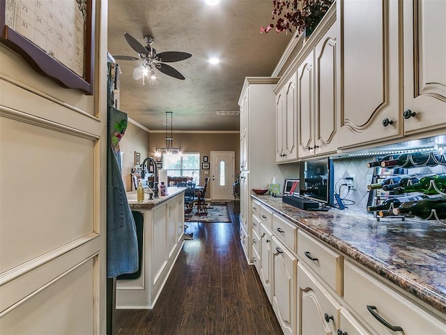 913 E Harrison Ave, Guthrie, OK 73044 - kitchen with a ceiling fan, ornamental molding, cream cabinets, dark wood-type flooring, and hanging light fixtures