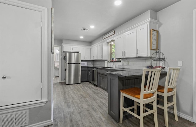 109 W 6th St, Amber, OK 73004 - kitchen with appliances with stainless steel finishes, white cabinets, decorative backsplash, a peninsula, and gray cabinetry