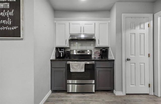 109 W 6th St, Amber, OK 73004 - kitchen with stainless steel electric stove, under cabinet range hood, tasteful backsplash, and light wood-style flooring