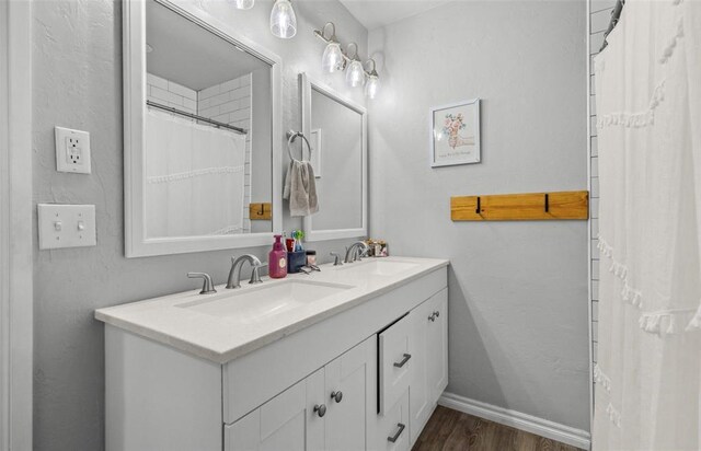 109 W 6th St, Amber, OK 73004 - bathroom featuring double vanity, wood finished floors, and baseboards