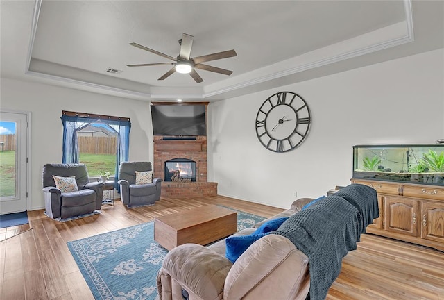 13640 Ridge View Ln, Edmond, OK 73025 - living area with a raised ceiling, a fireplace, ceiling fan, and light wood-style floors