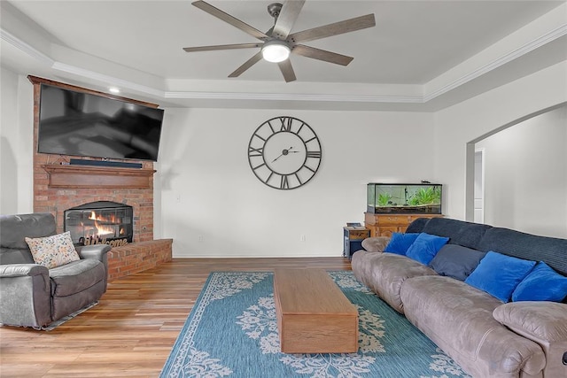 13640 Ridge View Ln, Edmond, OK 73025 - living room with ceiling fan, wood finished floors, a fireplace, a raised ceiling, and crown molding